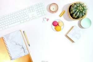 Minimalist office desk setup with cactus, keyboard, and colorful macarons for a modern aesthetic.